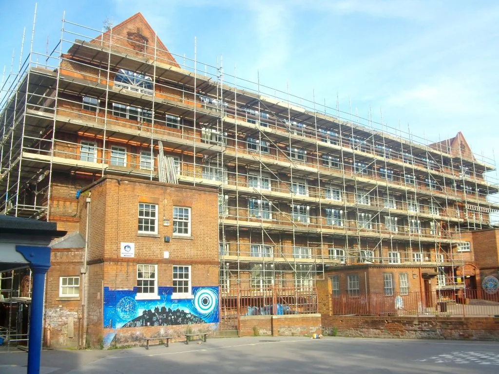 Scaffold covering a school building elevation, showing edge protection and full platform decking